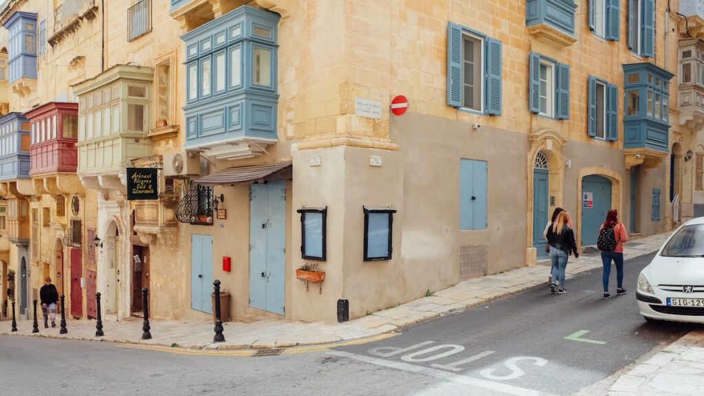 People walking next to Maltese balconies in the capital of Malta, Valletta