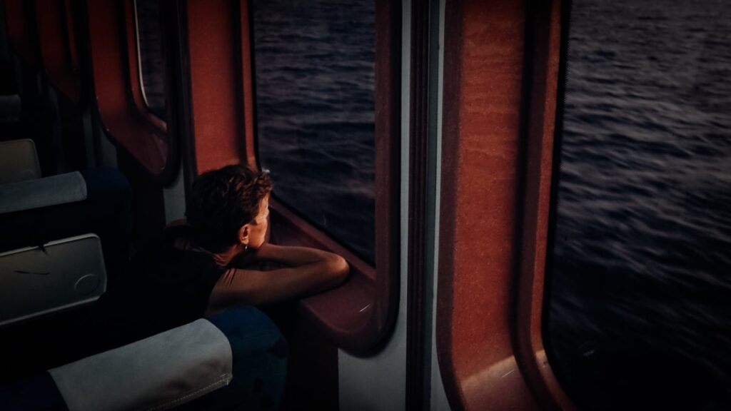 A woman on a ferry watching the sunrise