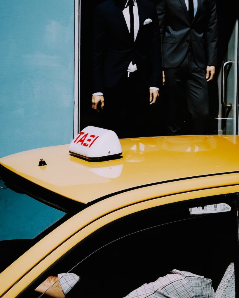 An image depicting a Greek taxi driver and a shop selling suits. Street photography in Athens