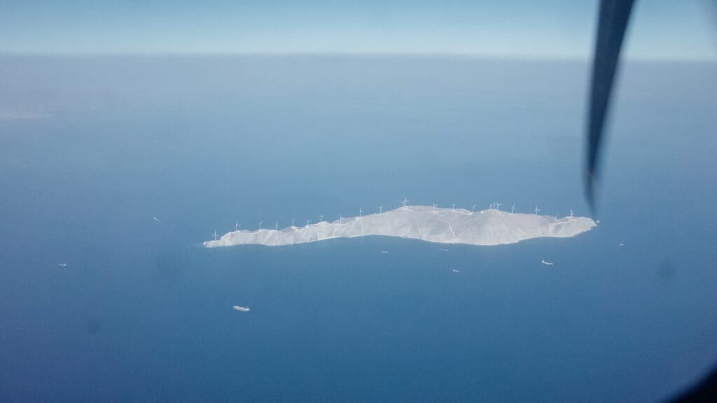 A photo of a small Greek island seen from a plane window