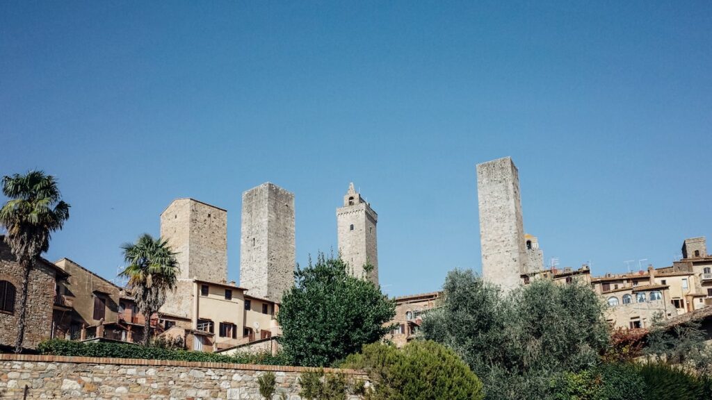 A photo of the San Gimignano skyline with some towers under the blue sky.