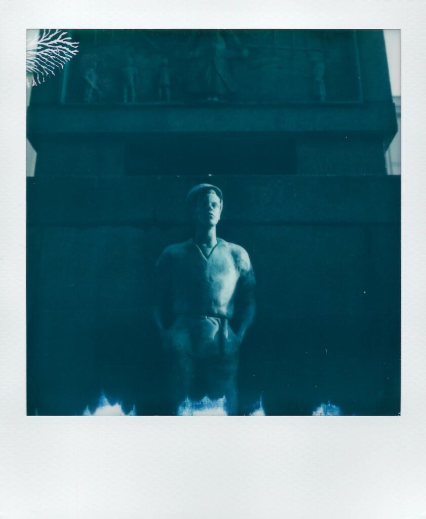 An image taken with the Polaroid SX-70, presenting the statue of a man. It belongs to the Sea Memorial located in Bergen, Norway.