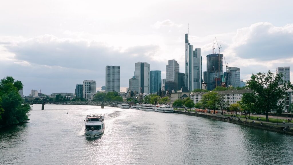 A photo of a boat cruising the Main River and the city's skyscrapers in the background. A cruise is one of the best things to do on a Frankfurt layover