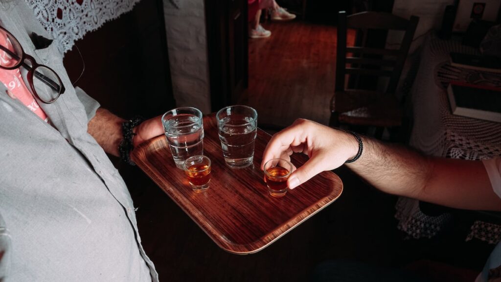 A photo of glasses containing water and psimeni raki, a local alcoholic drink served to the visitors of Hozoviotissa Monastery in Amorgos. The drinks are prepared by Orthodox monks.