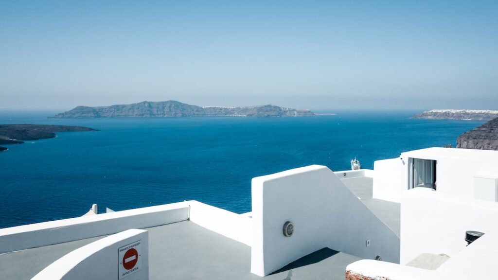 A photo showing whitewashed walls in Santorini, Greece. A cruise ship is on the background. Santorini shore excursions