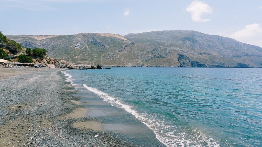 An image of the stunning black beach of Platis Yialos in Kalymnos, Greece. Swimming there is one of the best things to do in Kalymnos.
