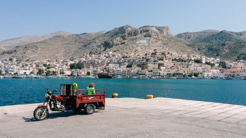 A photo of a man on a moped overlooking the port of Potha Town, the main port of Kalymnos, Greece