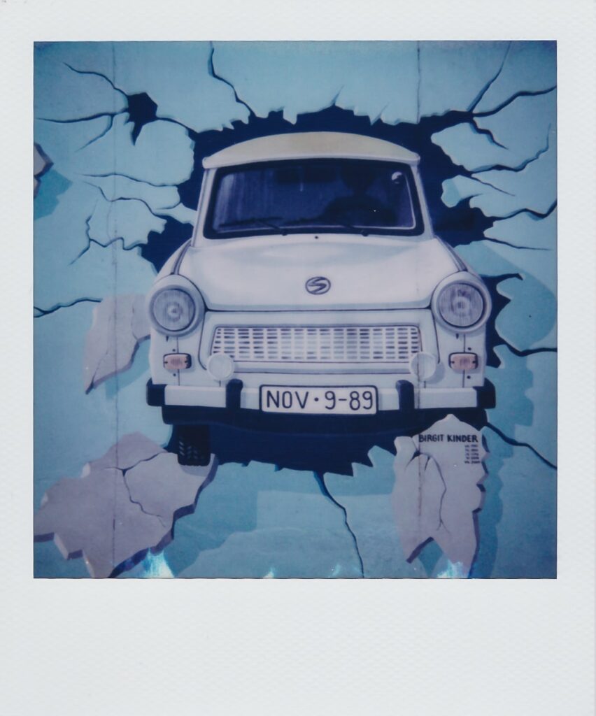 A polaroid of a mural in the East Side Gallery in Berlin, Germany, portraying a car, taken with the Polaroid Sun 660