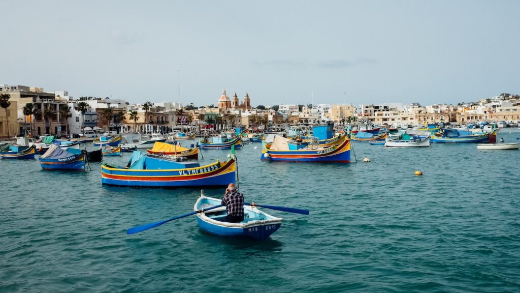 A photo of a man rowing a boat at the port of Marsaxlokk in Malta. The image is taken with the Ricoh GR ii.