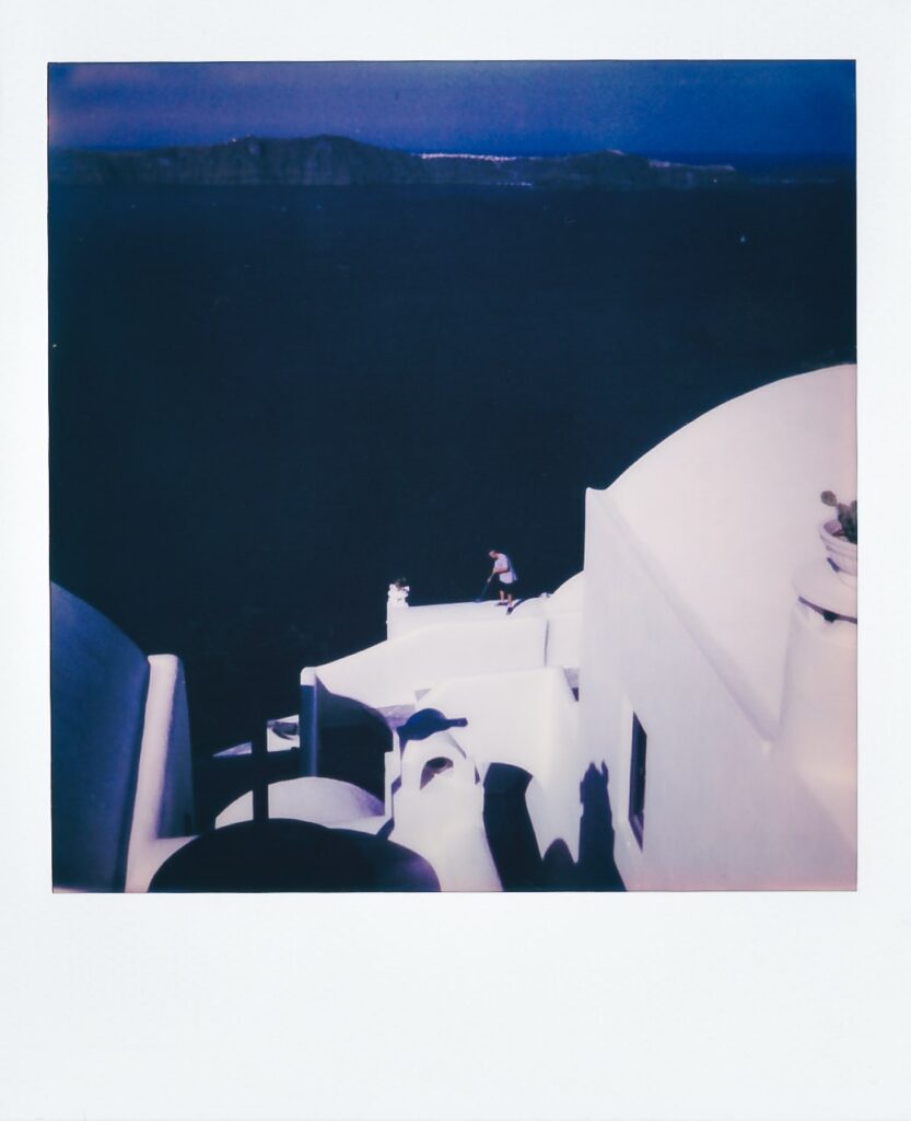 A polaroid of a man cleaning a roof in Santorini, Greece, taken with the Polaroid OneStep+