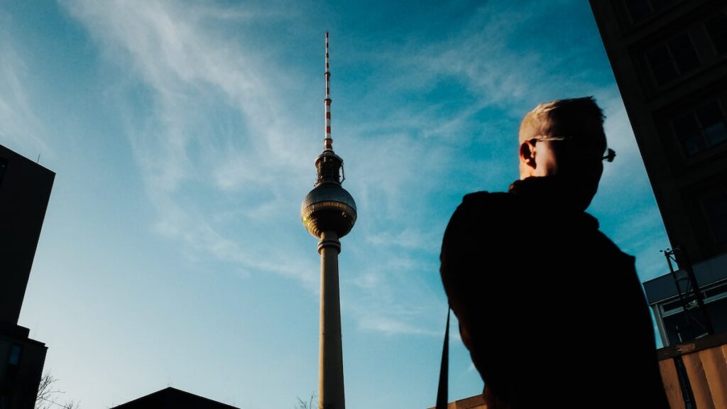 A man walking close to the TV Tower in Berlin, Germany, one of the best places to start exploring Berlin by bike.
