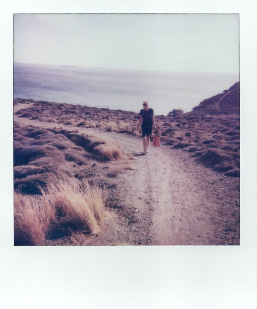 A polaroid of Barbara walking in the landscape of Anafi, taken with the Polaroid Impulse AF.