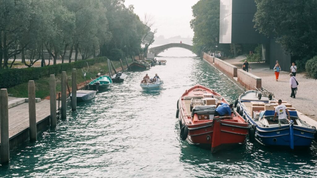 A photo showing a boat crossing the inner canal of the Giardini di Biennale in Venice, Italy