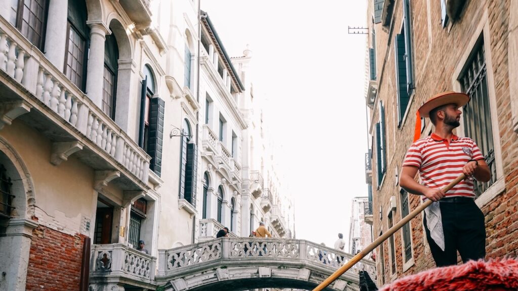 A photo showing a Venetian gondolier wearing a white and red shirt during work