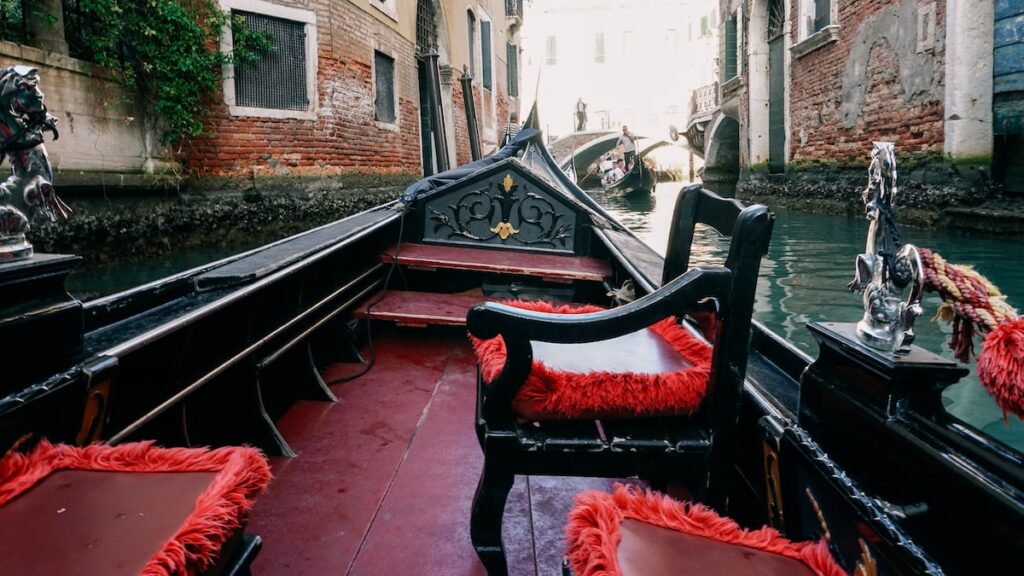 A photo showing a traditional gondola ride in Venice and the gondola's chairs and ornaments