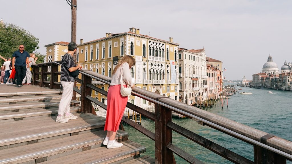 A photo showing people enjoying the views of Santa Maria Della Salute from Ponte Dell'Accademia in Venice, Italy