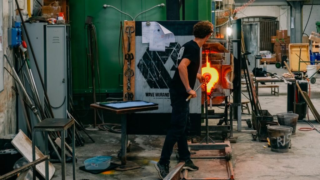 A photo showing the interior of glassmaking factory in Murano, Venice, and a man working