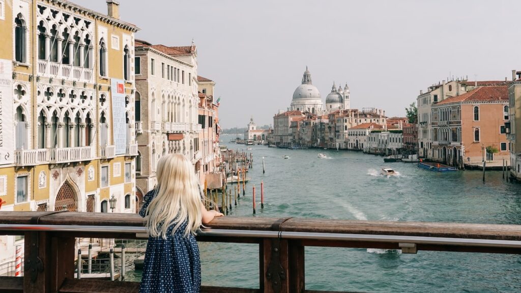 A photo showing a young girl standing at the Ponte Dell'Accademia in Venice and looking towards the Santa Maria Della Salute Cathedral