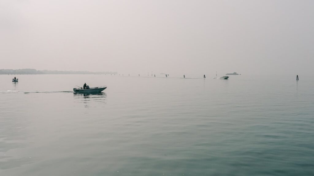 A photo showing a boat driving through the fog in Lido, Venice