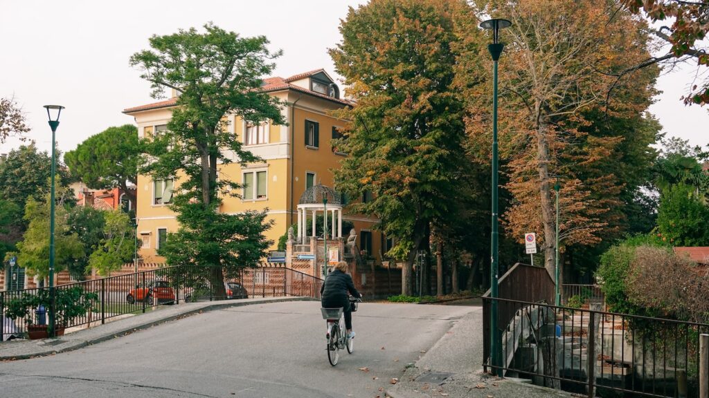 A photo showing a biker crossing a bridge and a Liberty-style villa in the background in Lido, Venice