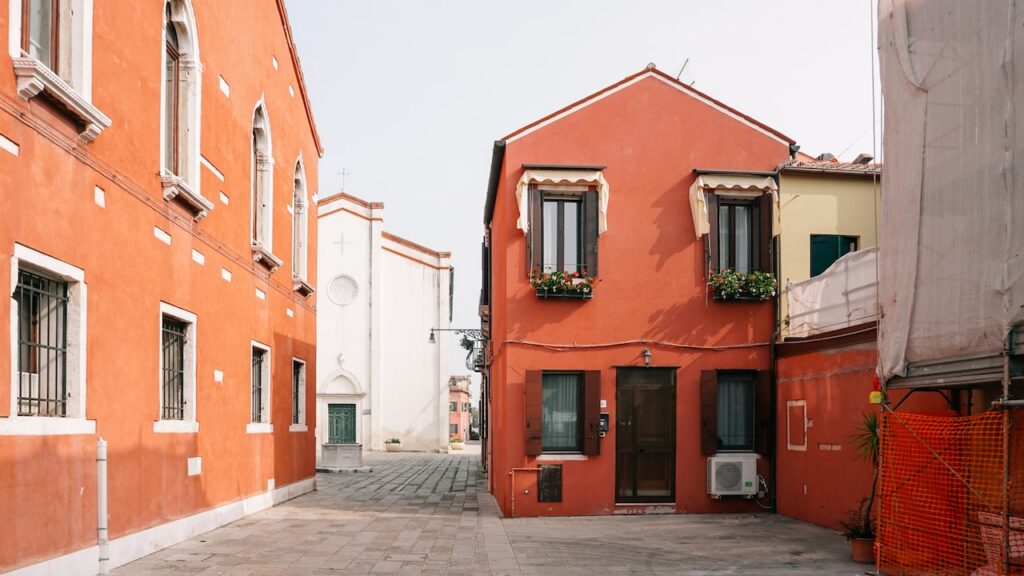 A photo showing the colorful houses at Malamocco, Lido, and the Santa Assunta Church in the background