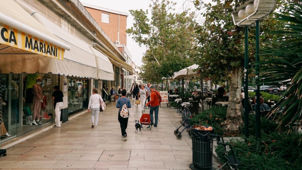 A photo of the Santa Maria Elisabetta Street in Lido, also known as the Gran Viale, with people walking and the Pizzaria Ristorante Lido on the right.