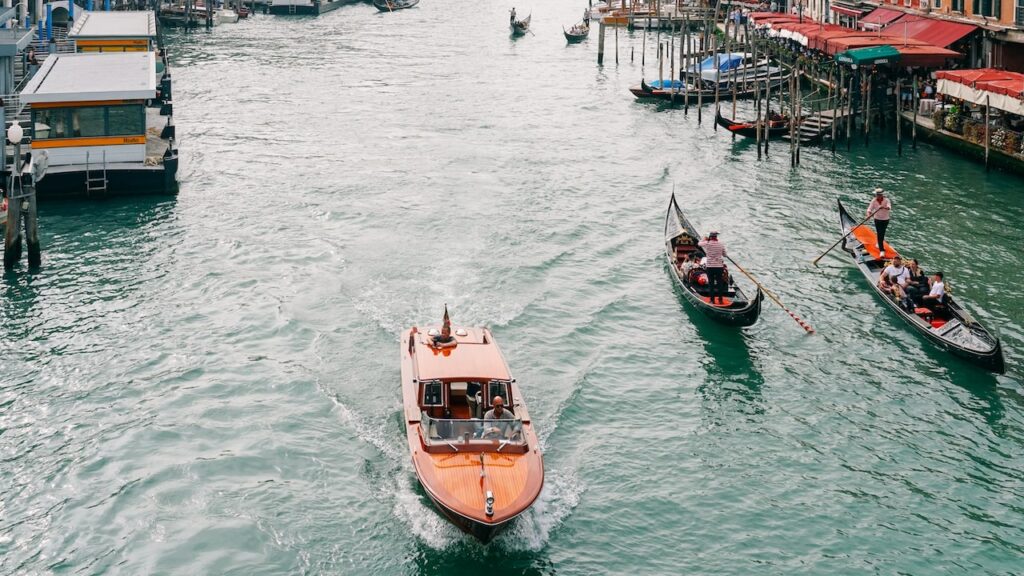 A water taxi and two gondolas seen from the Rialto Bridge in Venice, Italy