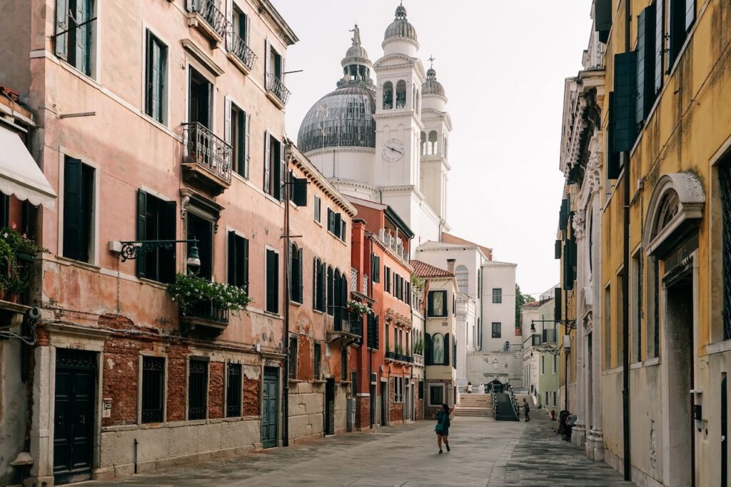 A woman walking in Dorsoduro, Venice, in front of the Santa Maria della Salute church. Dorsoduro is one of the best areas to stay in Venice for art lovers