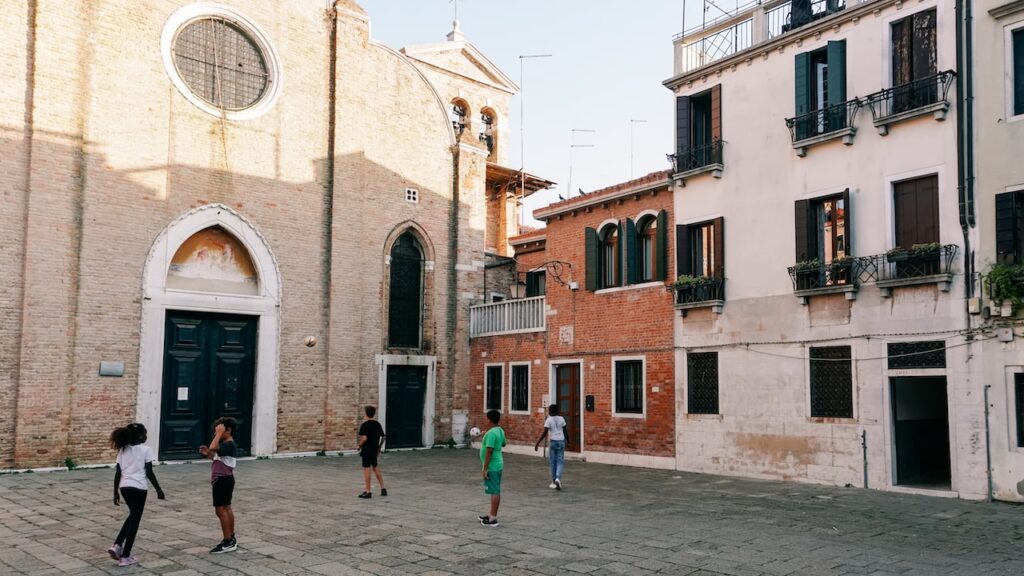 Kids playing football in front of a church in Venice, Italy