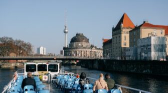 A photo of people on a River Spree boat tour in Berlin, with the TV Tower in the background. The image serves as a cover for an article about a Berlin River Cruise written by George Pavlopoulos for the travel blog Letters to Barbara