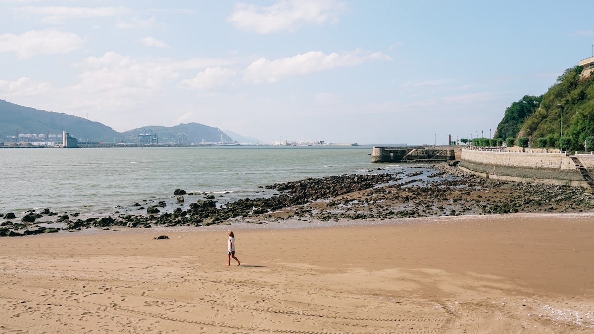 A woman walking along the Ereaga Beach