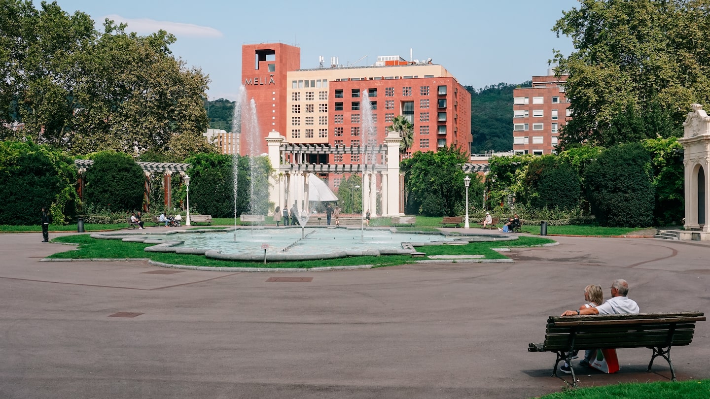 People enjoying their free time in front of a fountain in Bilbao. The image serves as the cover photo about an article for the 10 best things to do in Bilbao written by George Pavlopoulos for the travel blog Letters to Barbara