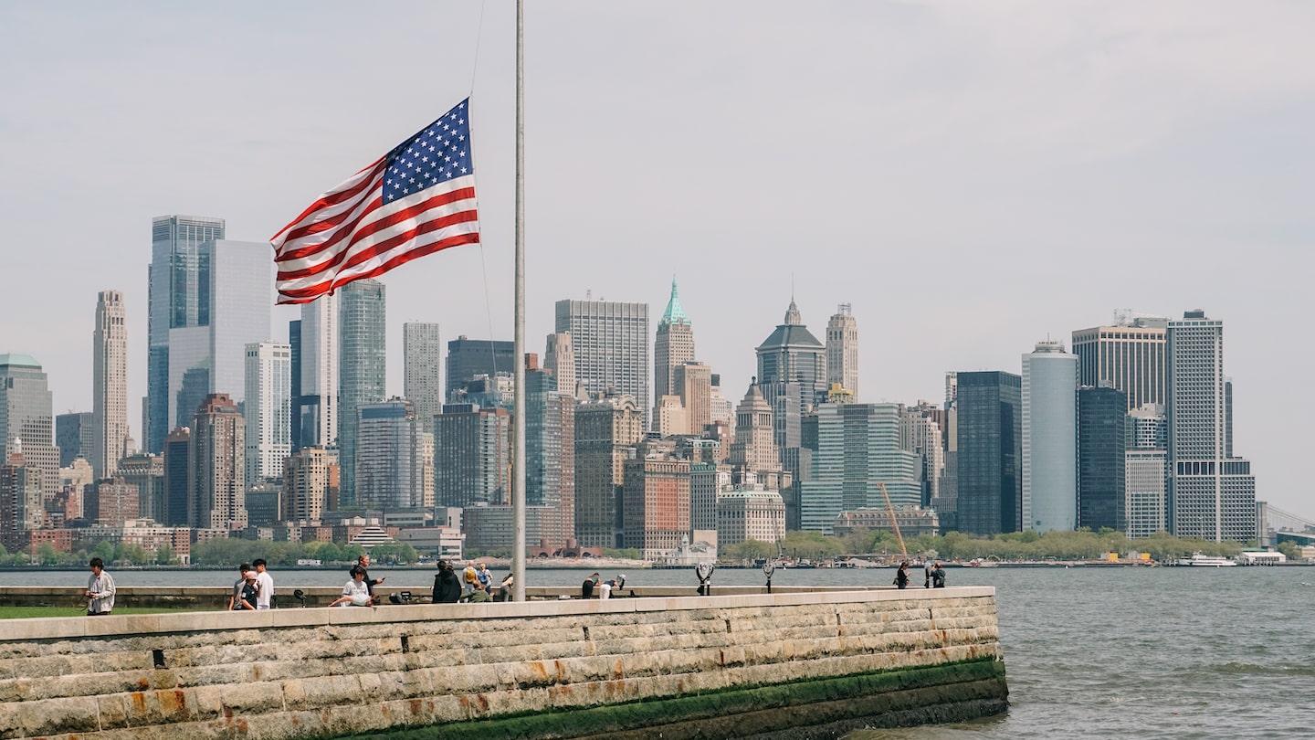 An American flag at Ellis Island the Manhattan skyline in the background