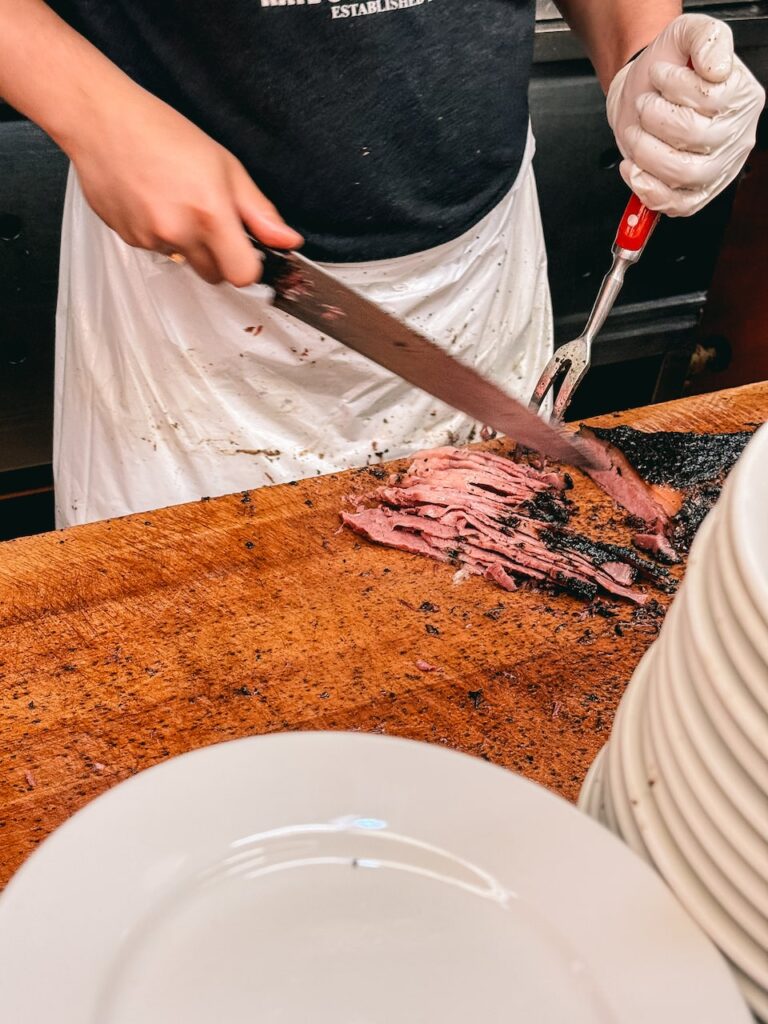 A man cutting slices of pastrami for a sandwich at Katz's in NYC