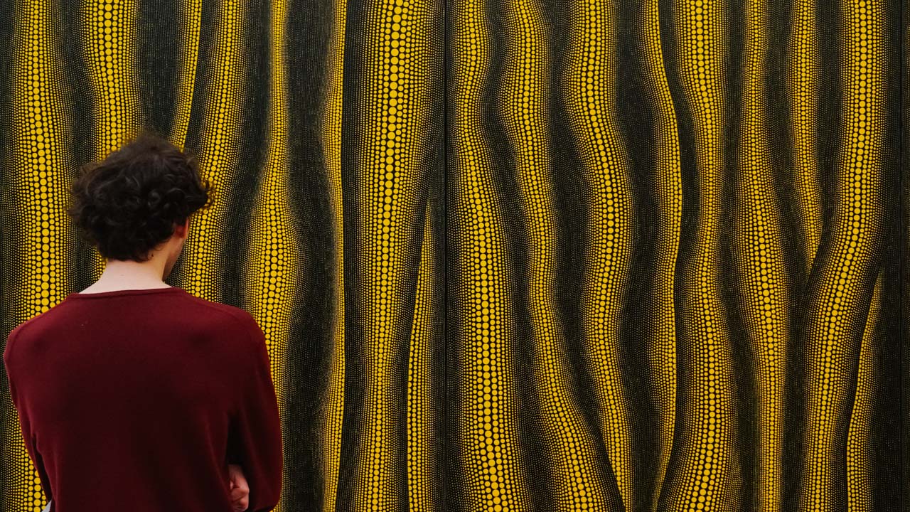 A man starring at a painting by Yayoi Kusama at Fondation Beyeler