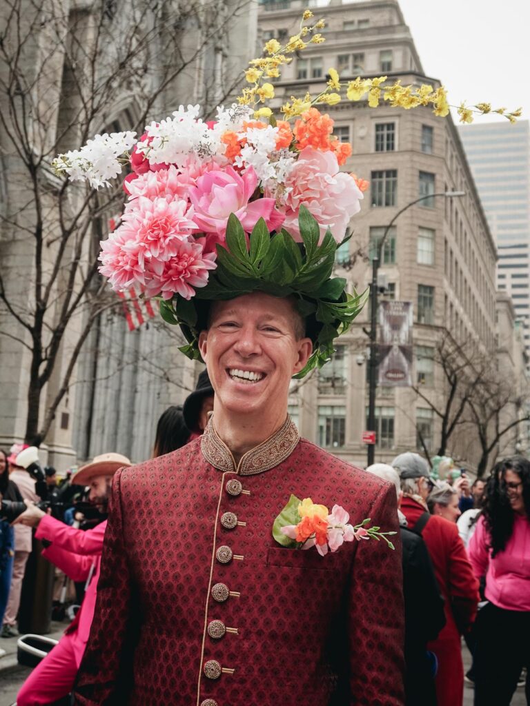 A man wearing a floral hat posing for a portrait during the New York Easter Parade and Bonnet Festival