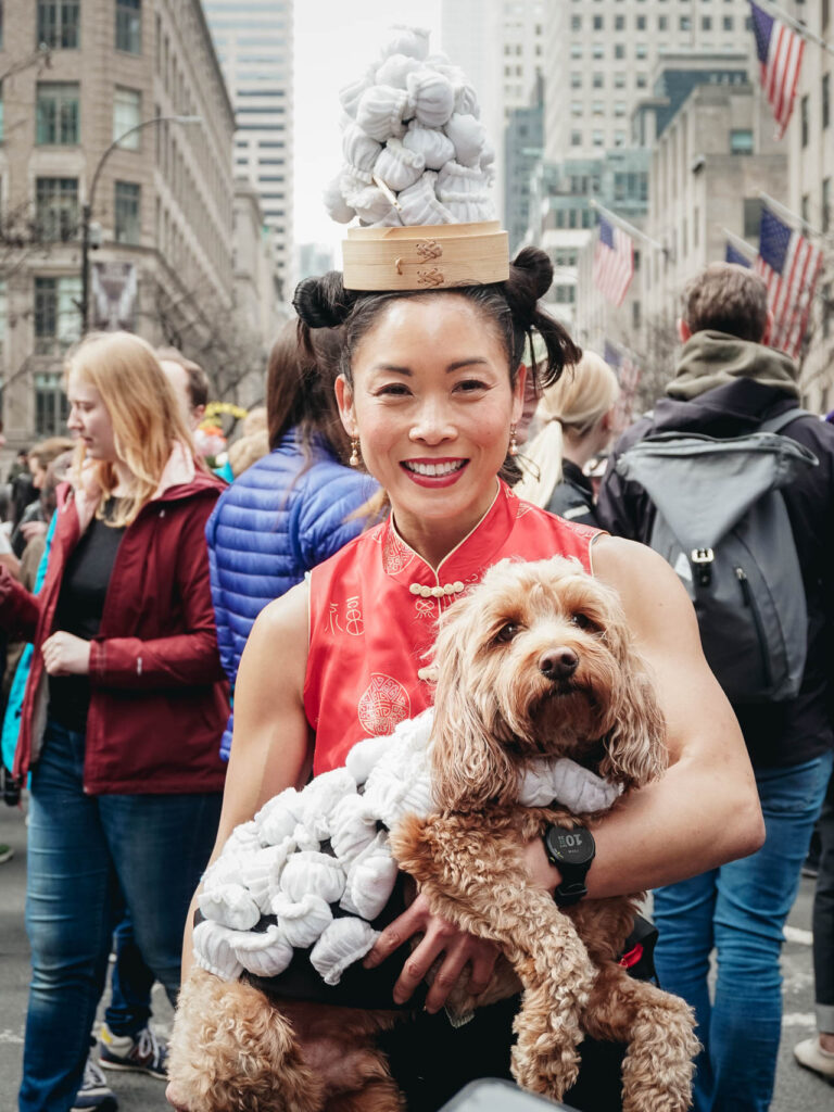 A woman with a dog posing for a street photography portrait during the New York Easter Parade Bonnet Festival