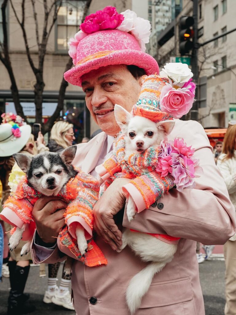A man holding two small dogs posing for a street photography portrait during the New York Easter Parade Bonnet Festival